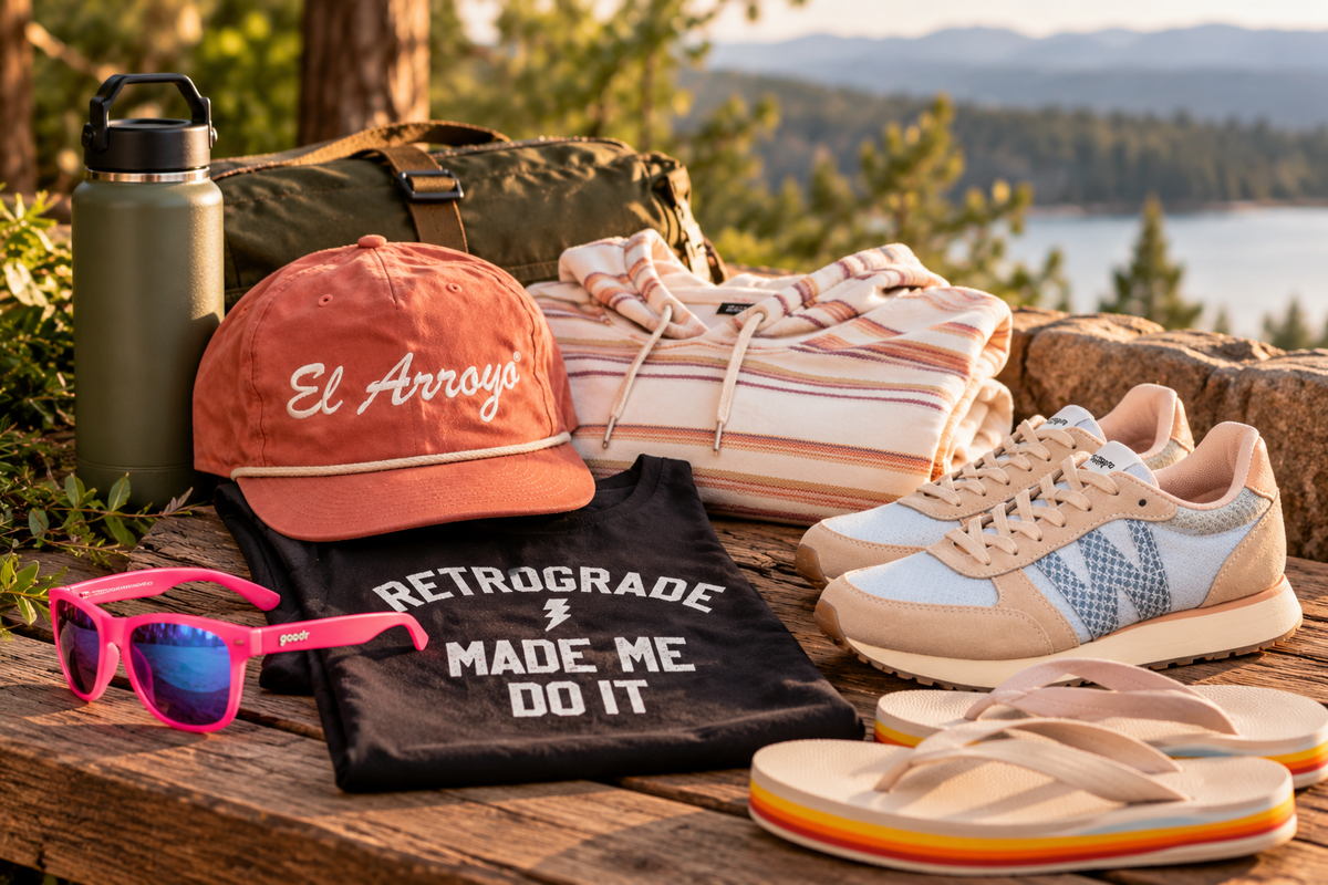 Outdoor apparel, footwear and accessories arranged on a rustic table, featuring Magnolia Trail brands and outdoor lifestyle essentials.